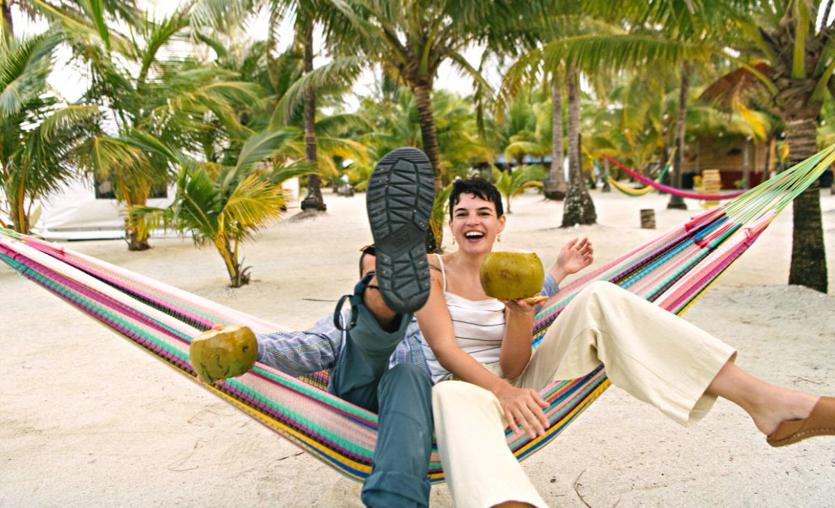 Couple enjoying Glover's Reef on a hammock while sipping on a coconut